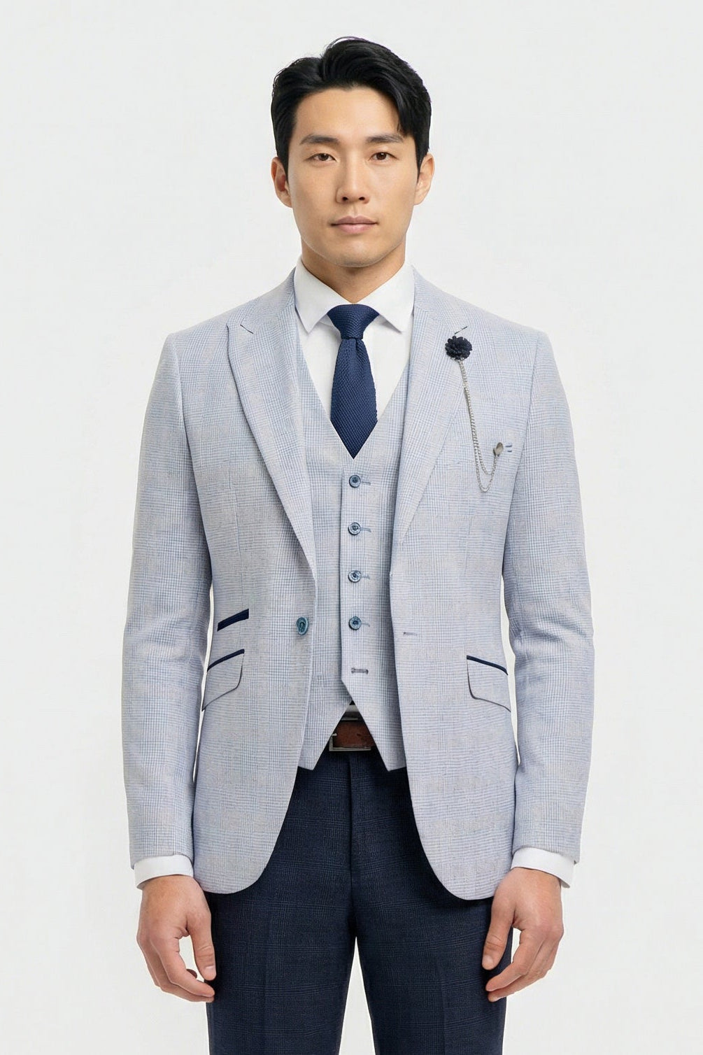 Uomo che indossa un blazer grigio chiaro, un gilet blu navy e una cravatta blu scuro su sfondo bianco