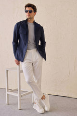 Completo da uomo elegante e casual composto da giacca safari in misto cotone blu navy e pantaloni bianchi.