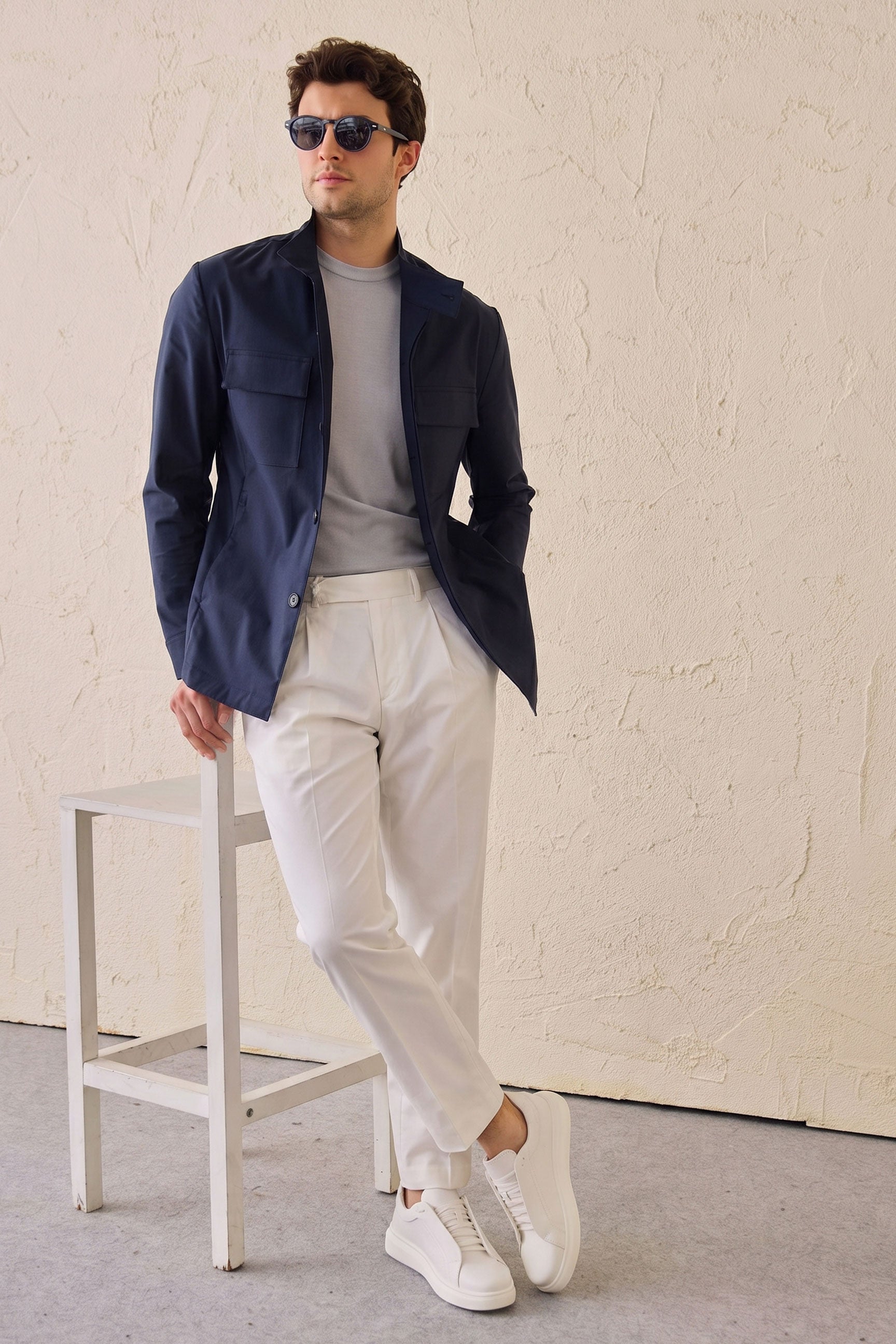 Completo da uomo elegante e casual composto da giacca safari in misto cotone blu navy e pantaloni bianchi.