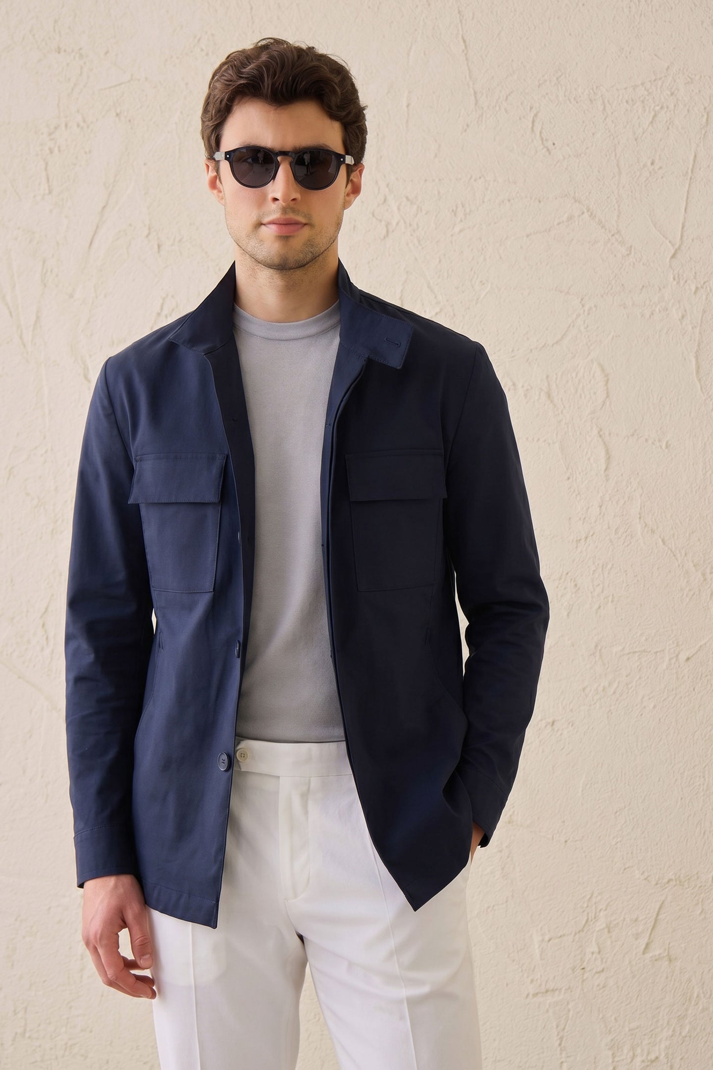 Completo da uomo elegante e casual composto da giacca safari in misto cotone blu navy e pantaloni bianchi.