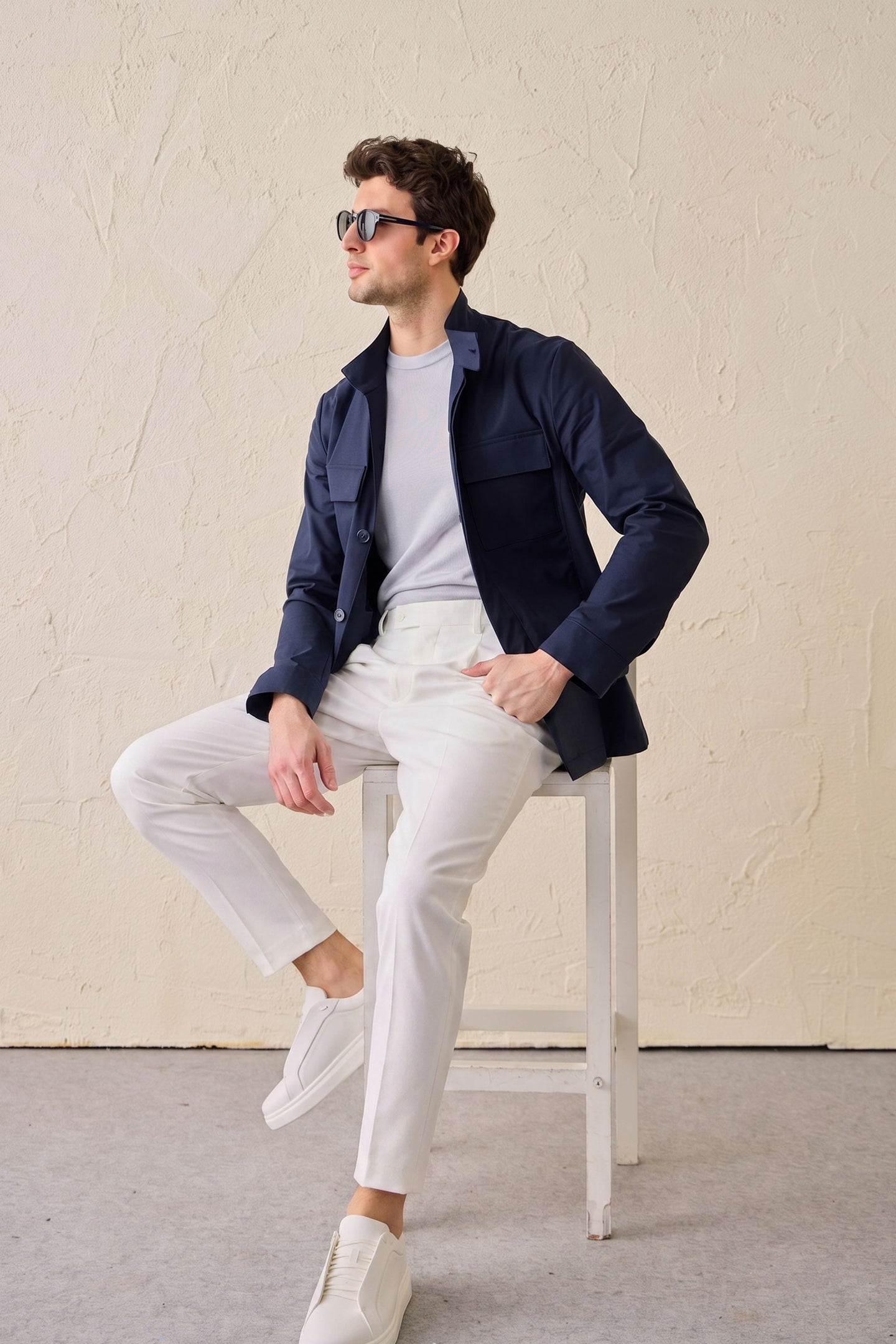 Completo da uomo elegante e casual composto da giacca safari in misto cotone blu navy e pantaloni bianchi.