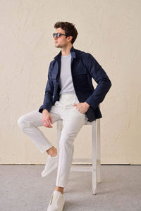 Completo da uomo elegante e casual composto da giacca safari in misto cotone blu navy e pantaloni bianchi.