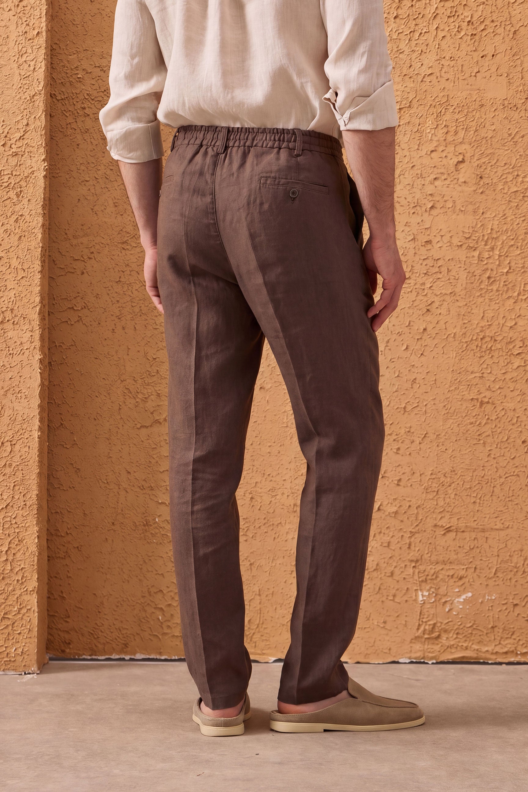Completo estivo da uomo composto da giacca in lino beige con zip e pantaloni marroni, elegante e casual.