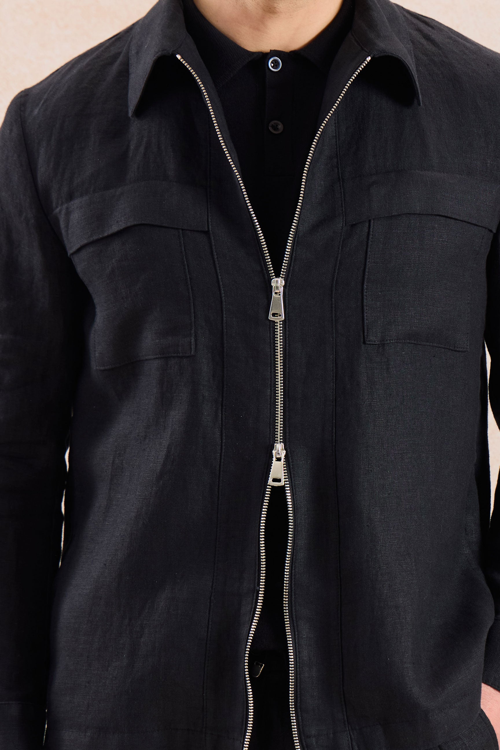 Completo estivo da uomo composto da giacca in lino nera con zip e pantaloni beige, elegante e casual.