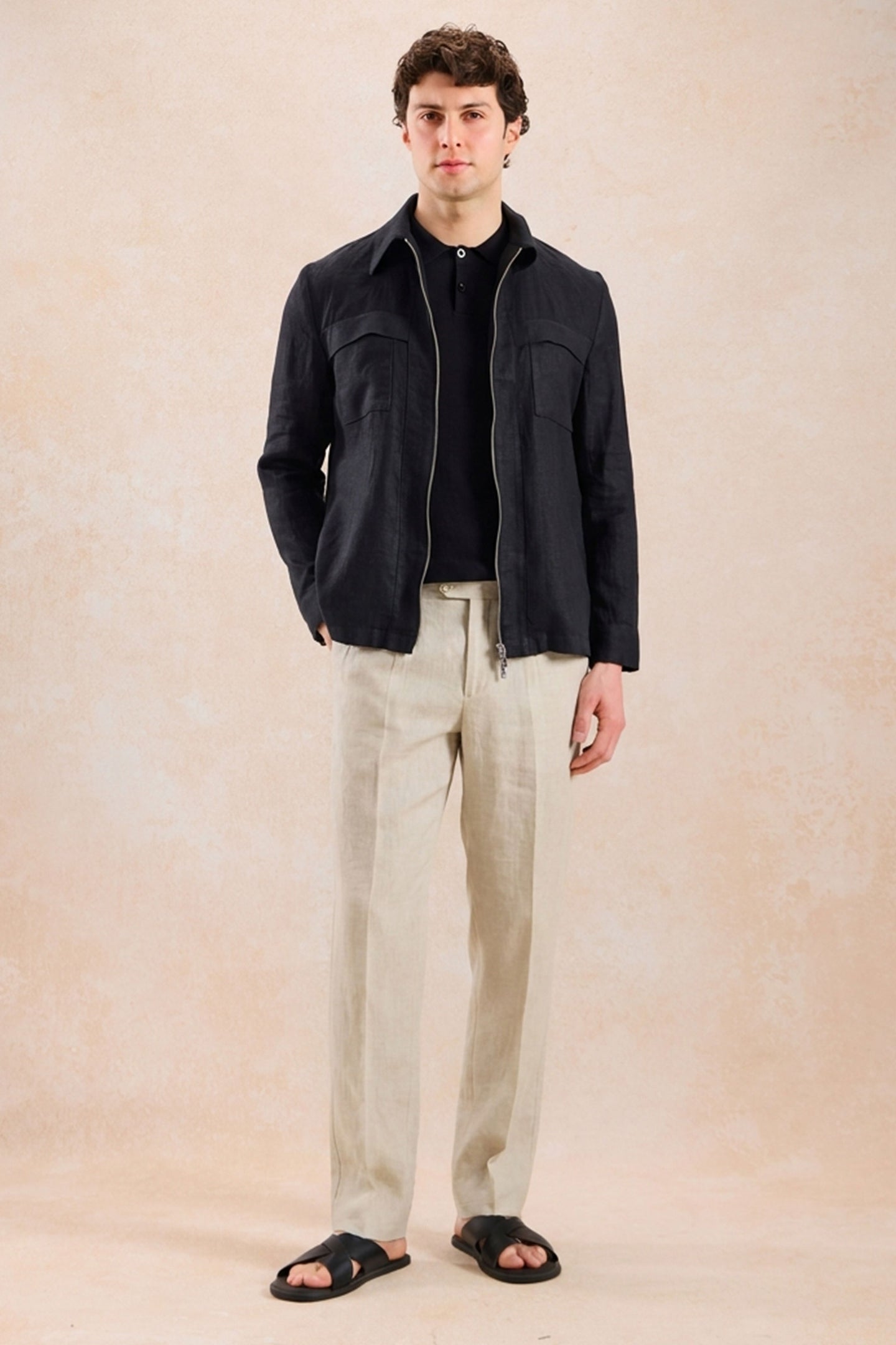 Completo estivo da uomo composto da giacca in lino nera con zip e pantaloni beige, elegante e casual.