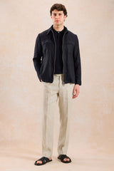 Completo estivo da uomo composto da giacca in lino nera con zip e pantaloni beige, elegante e casual.