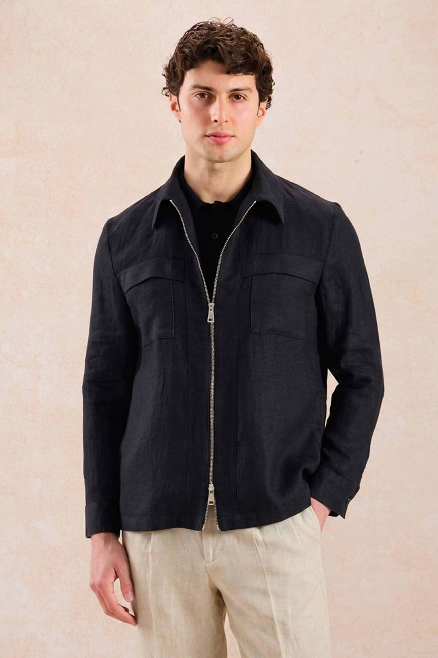 Completo estivo da uomo composto da giacca in lino nera con zip e pantaloni beige, elegante e casual.
