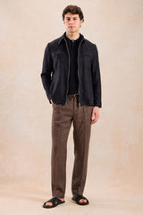 Completo estivo da uomo composto da giacca nera con zip in lino e pantaloni marroni, elegante e casual.