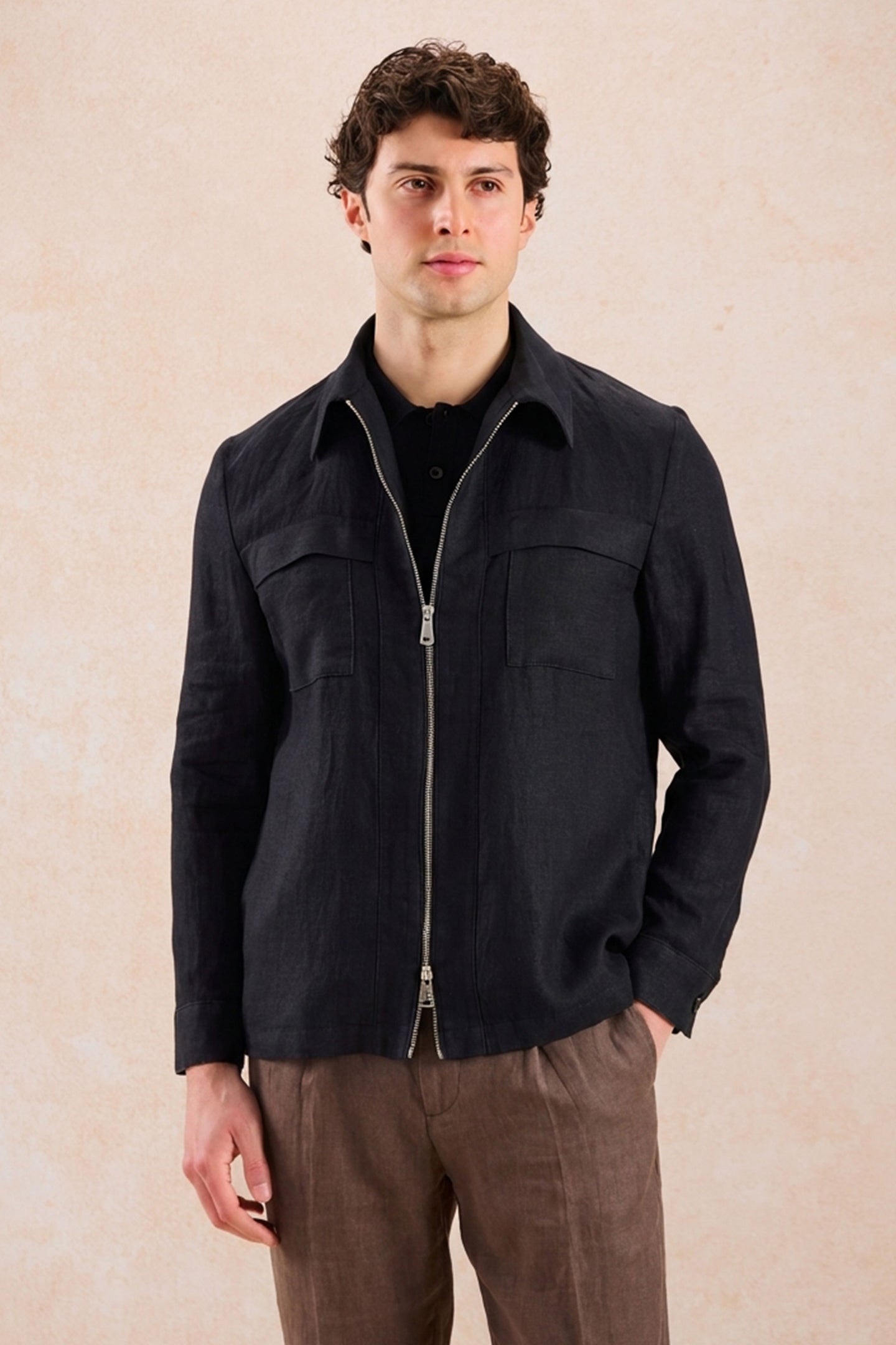 Completo estivo da uomo composto da giacca nera con zip in lino e pantaloni marroni, elegante e casual.