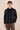 Completo estivo da uomo composto da giacca nera con zip in lino e pantaloni marroni, elegante e casual.