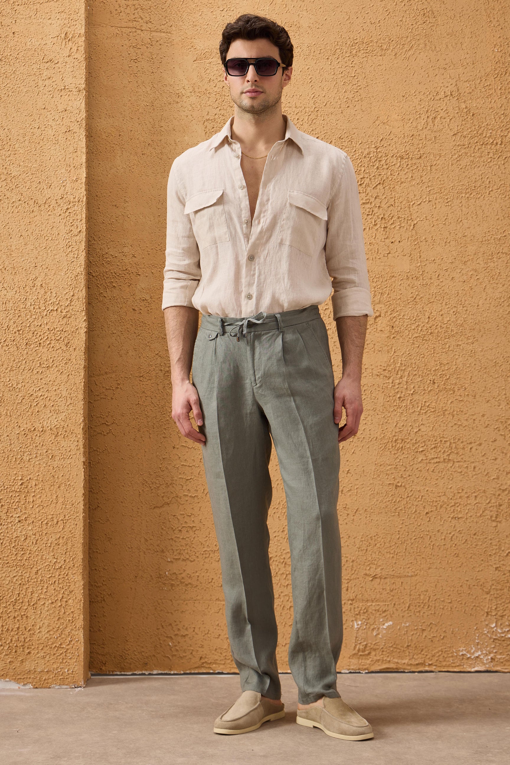 Completo estivo da uomo composto da giacca in lino blu navy con zip e pantaloni color salvia, elegante e casual.