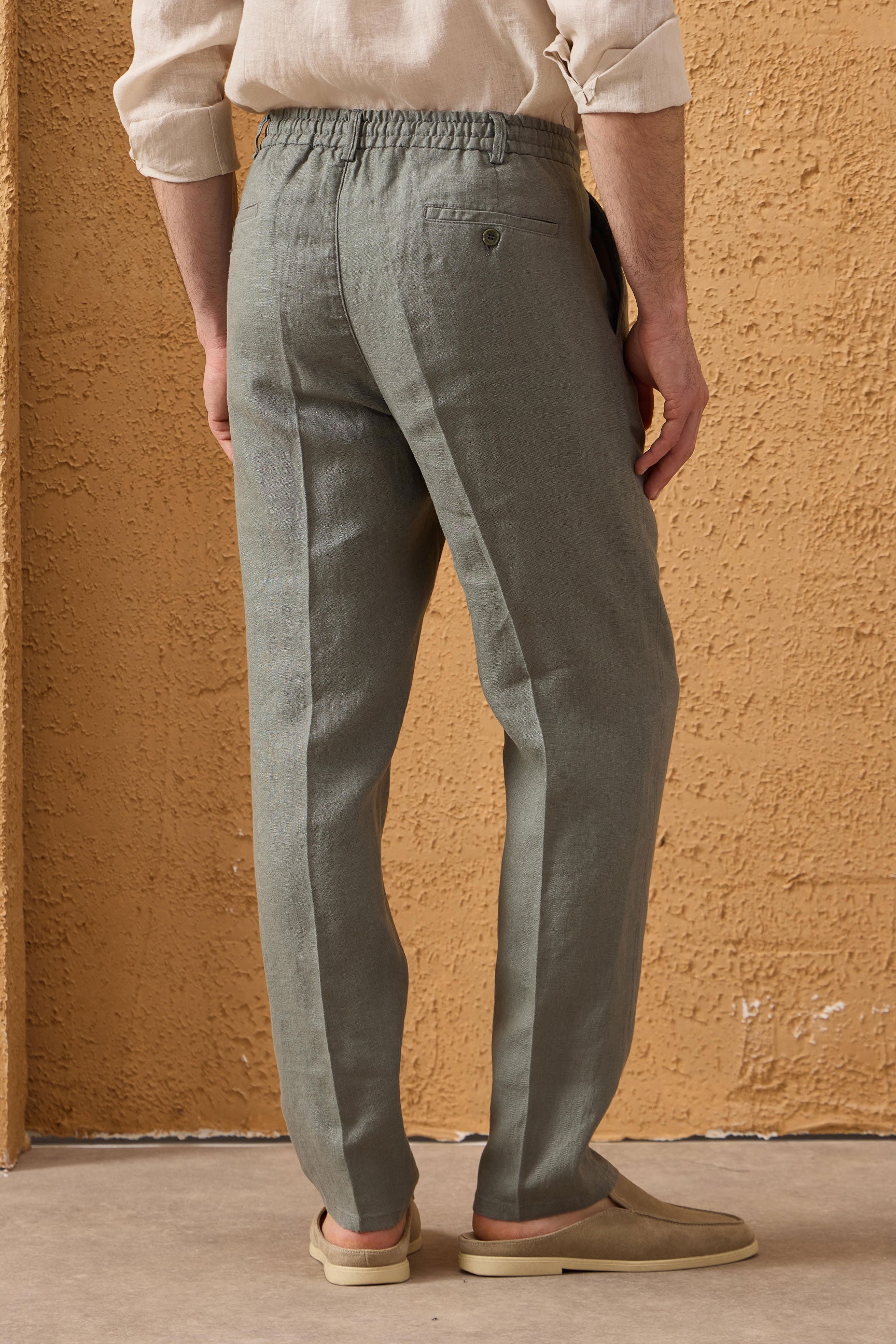 Completo estivo da uomo composto da giacca in lino blu navy con zip e pantaloni color salvia, elegante e casual.