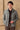 Completo estivo da uomo composto da giacca in lino verde salvia con zip e pantaloni marroni, elegante e casual.